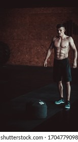 Strong Man Doing Training With Sandbag At The Gym.