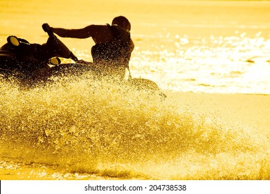 strong man drive on the jet ski above the water at sunset .silhouette. spray.