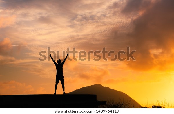 Strong man with fist in the air standing on top a mountain. Triumph, victory and feeling determined.