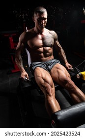 Strong Man In The Gym And Exercising Quadriceps And Glutes On Machine - Muscular Athletic Bodybuilder Fitness Model Exercise