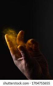 Strong Man Hand Sprinkling And Scattering Yellow Turmeric Which Is Famous Eastern Seasoning On Dark Background With Strong Light With His Fingers And Palm Making Amazing Nice Dust