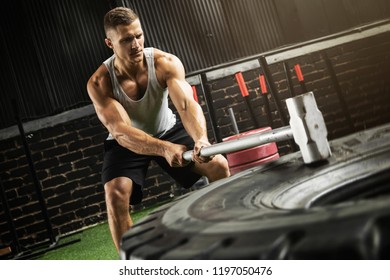 Strong Man Is Hitting Tire With A Sledgehammer During His Training Workout