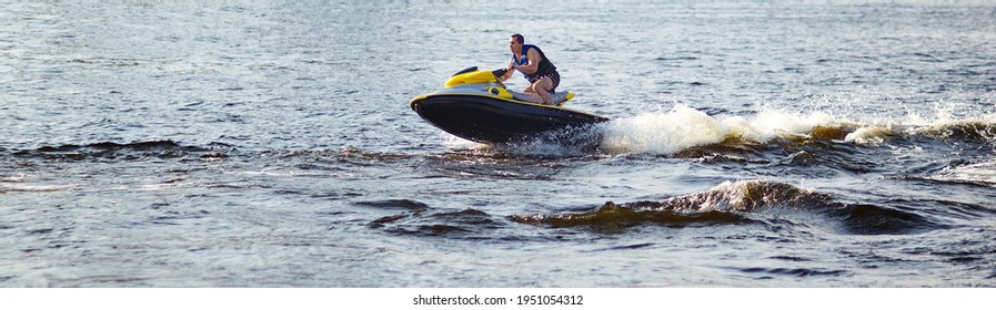 Strong Man Jumps On The  Water Scooter Above The Water. Man Speeding On Powerboat On Lake During Summer Vacation