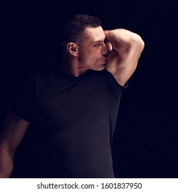 Strong Man Looking And Kissing His Self Biceps Arm On Dark Black Background. Closeup Portait. Toned