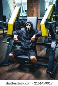 Strong Man In Mask Posing In The Gym. Male Person Wearing Screaming Mask Training At The Gym.