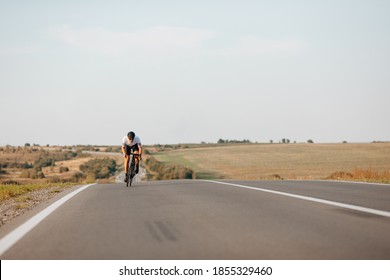 Strong Man In Sport Clothing, Protective Helmet And Glasses Riding Bike On Fresh Air. Muscular Cyclist Practicing In Long Distance Racing.