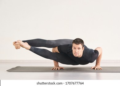 Strong man stand at Astavakrasana. Fitness yoga exercise. Pilates asana. Male gymnast home class. Online isolation personal teacher. Sportsman balance health banner. Horizontal with copyspace.