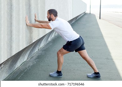 Strong Man Stretching Calf and Leaning on Wall