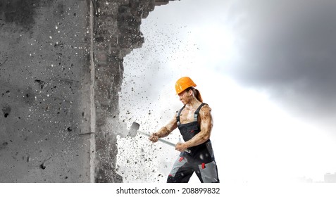 Strong Man In Uniform Breaking Wall With Hammer