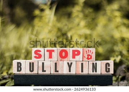 A strong message to prevent bullying and concisely conveyed through wooden cubes stacked on a dark surface with a blurred natural background