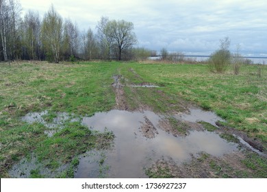 Strong mud on a rural road. Water on the field and country road.Rural landscape with empty countryside dirt wet road. The harsh landscape nature and road through the fields with puddles and mud 