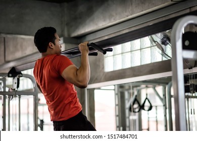 Strong Muscular Athletic Asian Man Perform Bodybuilding By Pulling Up Or Chin Ups On Horizontal Bar At Sport Gym. Hands, Arms, Shoulder Workout. Bodybuilding And Healthy Lifestyle Concept.