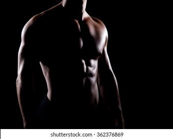 Strong And Muscular Body Of Man Shaded Over Black Background.