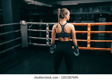 Strong muscular boxer woman standing in ring with boxing gloves on hands. Backs turned.