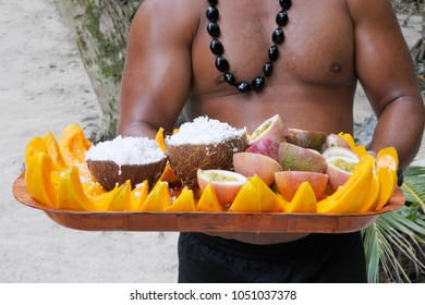 A Strong Muscular Cook Islander Man Serving Fresh Coconut And Papaya Fruit On A Tray In Rarotonga, Cook Islands. Food Background , Culture And Texture. Real People. Copy Space