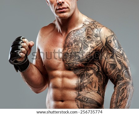 Strong muscular fighter with tattoo poses