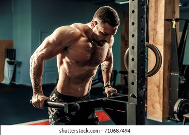 Strong muscular man doing push-ups on uneven bars in crossfit gym. Workout lifestyle concept. - Powered by Shutterstock