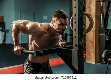 Strong Muscular Man Doing Push-ups On Uneven Bars In Crossfit Gym. Workout Lifestyle Concept.