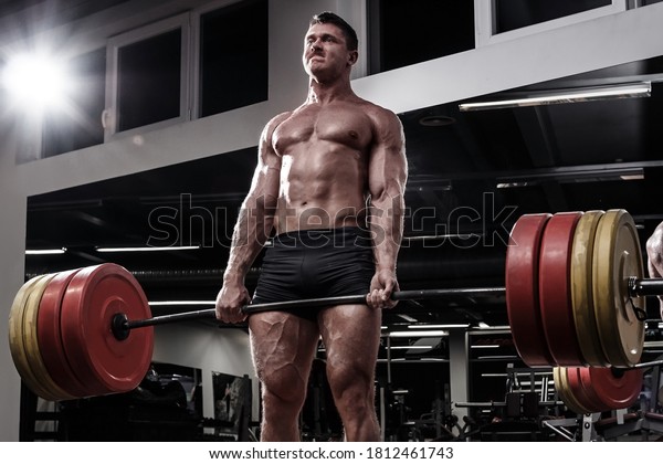 Strong\
and muscular powerlifter doing deadlift in a\
gym
