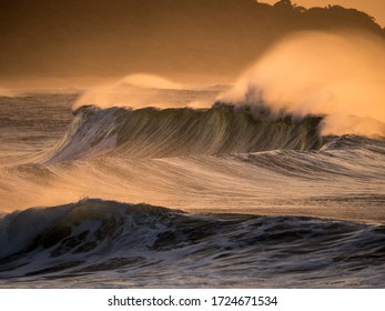 Strong Offshore Wind Blows Sea Spray Off The Tops Of Large Powerful Breaking Waves That Were Generated After A Storm.