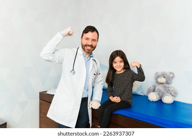 Strong pediatrician doctor and brave little girl doing a bicep curl looking happy after getting an allergy vaccine shot