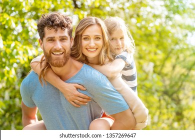 Strong And Reliable Man Supporting His Family By Carrying Wife And Son Piggyback 