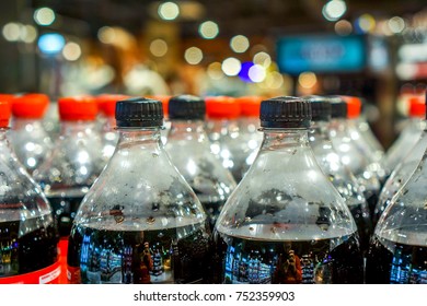 strong rows with clean plastic bottles with black sweet liquid. big army of bottles with red and black covers in grocery shop. plastic bottles with soft drinks background