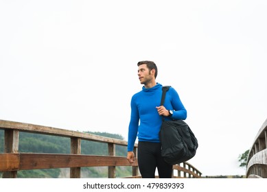 Strong Runner Man Arriving At His Outdoor Training Spot On A Cloudy Autumn Day With A Sport Bag. Fitness Sporty Male In Rodiles, Asturias.