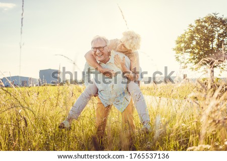 Strong senior man carrying his vital wife piggyback without back pain