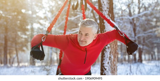 Strong Senior Man Doing Bungee Fitness Exercises, Working Out Outdoors On Winter Morning, Panorama. Mature Sportsman Training With Bodyweight Resistance Straps At Snowy Park