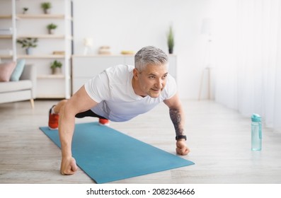 Strong senior man making strength workout, doing push ups on sports mat, exercising at home, copy space. Sporty elderly man training his body, leading active lifestyle - Powered by Shutterstock