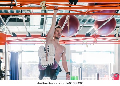 Strong Shirtless Male Athlete Shows Calisthenic Moves Hanging On Pull Bar One Arm Leg Raises Or L-sit Hold