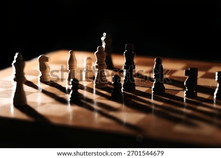 Strong side light casts long shadows as white and dark pieces face off; a moody chessboard scene about tension, balance and strategic positioning.