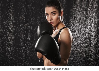 Strong Slim Woman Boxing Wearing Gloves And Standing In Defense Position Under Rain Drops Isolated Over Black Background