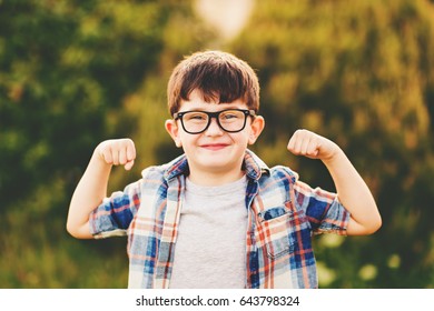 Strong, smart and funny little boy playing outdoors, wearing eyeglasses and blue plaid shirt