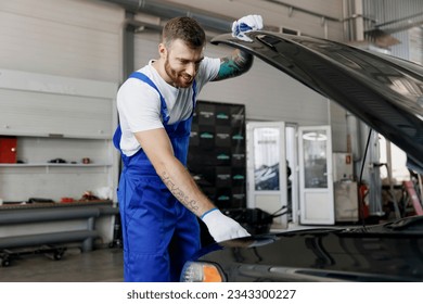 Strong smiling happy confident young male professional technician car mechanic man wears denim blue overalls white t-shirt raised hood bonnet work in light modern vehicle repair shop workshop indoors - Powered by Shutterstock