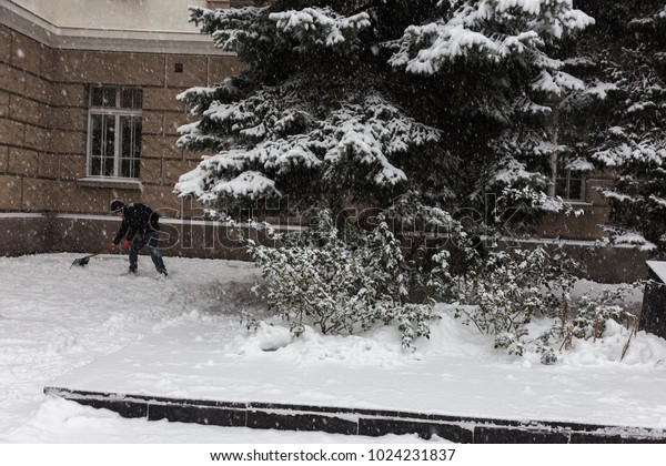 Strong snowfall in city streets in winter. Cars\
are covered with snow, slippery road. Bad weather in winter: heavy\
snow and blizzard. Pedestrians go under heavy snow. Winter and\
snowstorm, snowfall