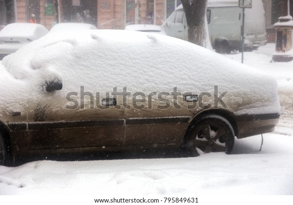 Strong snowfall in city streets in winter. Cars
are covered with snow, slippery road. Bad weather in winter: heavy
snow and blizzard. Pedestrians go under heavy snow. Winter and
snowstorm, snowfall