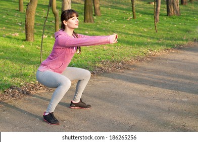 Strong sporty woman doing squat exercises outdoors on fresh air in the park on a sunny spring day. Copy space - Powered by Shutterstock