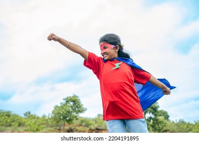 Strong Teenager Girl Kid In Flying Position Looking Around While Standing On Top Of Hill - Concept Of Imagination, Fantasy And Powerful.