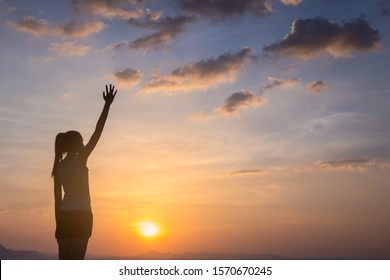 Strong, victorious and motivated young woman raising her fist up to the sunset sky.  - Shutterstock ID 1570670245