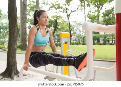 Strong Vietnamese woman performing L-sit exercise on parallel bars  - Powered by Shutterstock