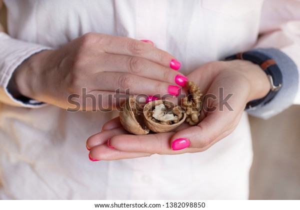 strong walnut in women\'s hands with manicured\
nails in pink colors