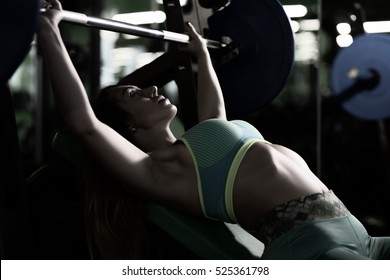 Strong Woman Doing Bench Press Exercise In Gym