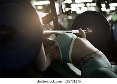 Strong Woman Doing Bench Press Exercise In Gym