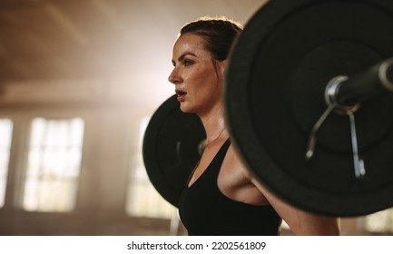 Strong woman exercising back squats with a barbell. Female doing squats with heavy weights. - Powered by Shutterstock