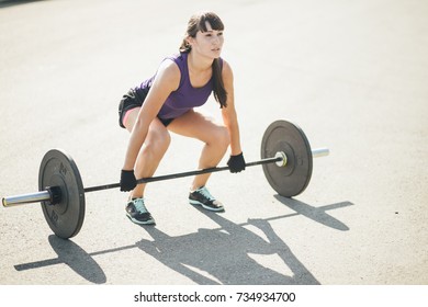 Strong woman exercising with barbell in gym. Cute girl preparing for weightlifting workout. Sports, fitness concept. - Powered by Shutterstock