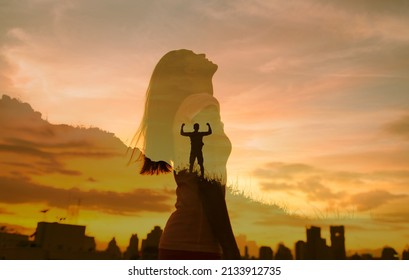 Strong woman and man, winning, success, willpower, and  life goals concept. Young female looking up to the sky, and male with arms flexed standing on a mountain facing the city.