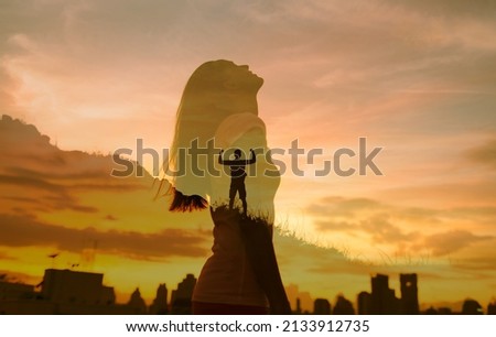 Strong woman and man, winning, success, willpower, and  life goals concept. Young female looking up to the sky, and male with arms flexed standing on a mountain facing the city.