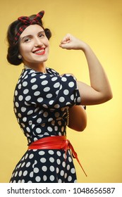 strong woman show her biceps on yellow background looking at camera